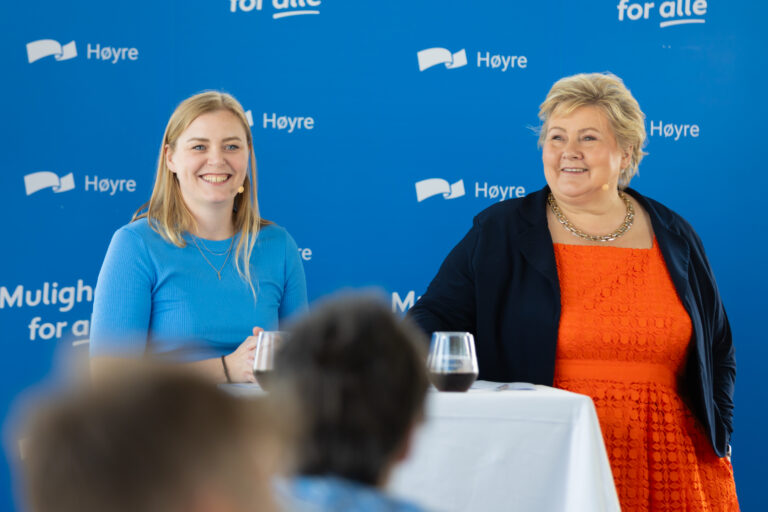 Erna Solberg og Tina Bru avbildet foran en blå vegg med Høyre-logo.