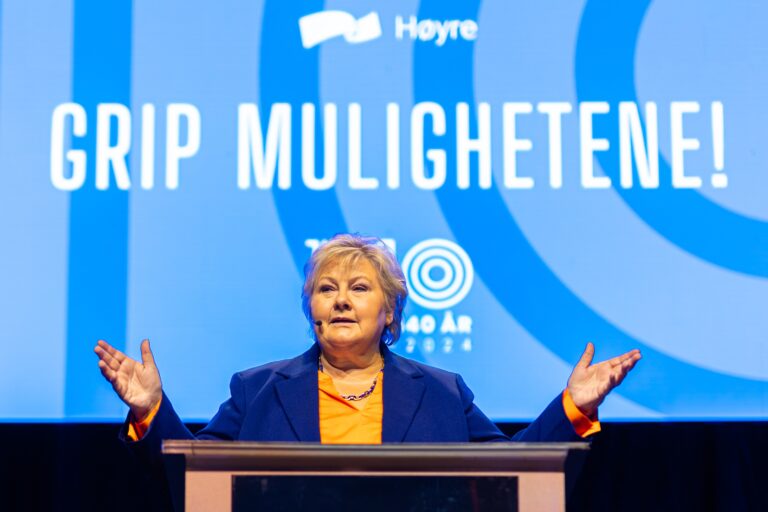 Erna Solberg. Med tekst der det står "Grip mulighetene" bak henne.