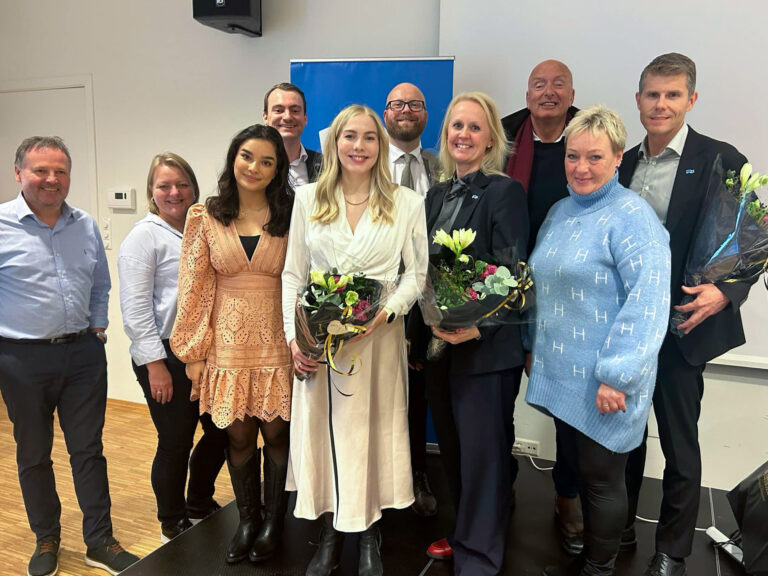 Gruppebilde av Melhus Høyres delegasjon til Sør-Trøndelag Høyres nominasjonsmøte til stortingsvalget, sammen med de valgte toppkandidatene som har blomsterbuketter i hendene. Alle smiler til kamera.