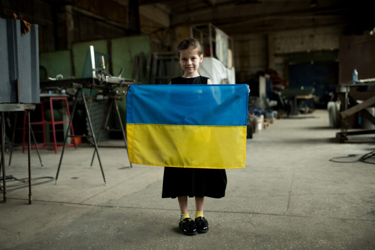 Ukrainian girl holds the Ukrainian flag at the volunteer center in Zaporizhzhia, Ukraine. June 14, 2022. photo: Elena Tita / the Collection of war.ukraine.ua